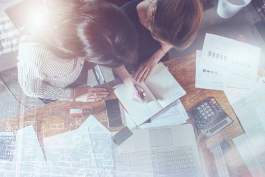 Masada oturup birlikte çalışan konsantre genç kadınların en iyi görüntüsü.