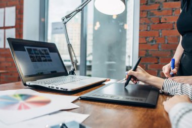 Bir grafik tablet ve modern ofisinde oturan bir dizüstü bilgisayar kullanarak bir proje çizim kadınların yakın çekim yansıma