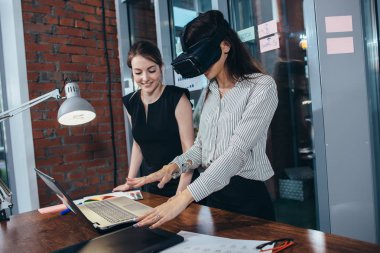 İki kız öğrenci sınıfta bir dersten sonra molası Vr gözlüklü 3d bir oyun oynuyor