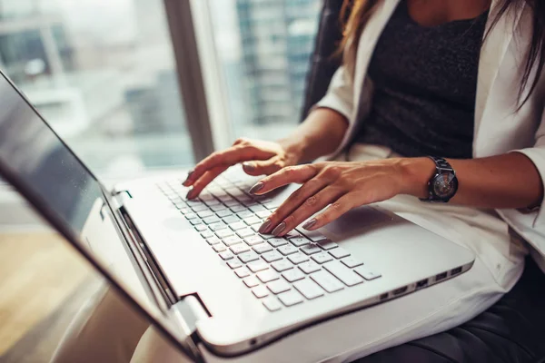 Vista de cerca de la mujer usando netbook sentado en la oficina —  Fotos de Stock