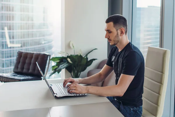 Mann sitzt am Arbeitsplatz und benutzt Laptop — Stockfoto
