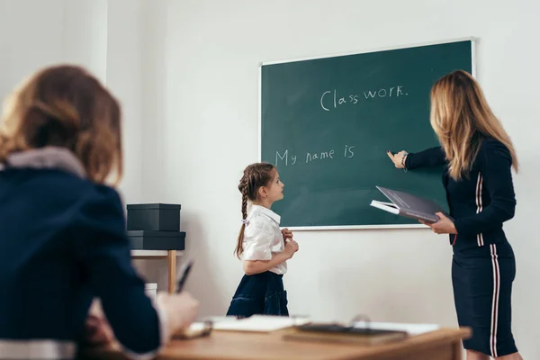 Skola Lektion lärare och elev skriva på en svart tavla — Stockfoto