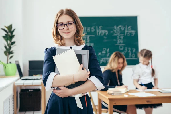 Porträt eines lächelnden Schulmädchens mit Büchern im Klassenzimmer — Stockfoto