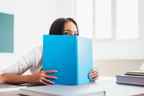 Belle étudiante se cachant derrière le livre — Photo