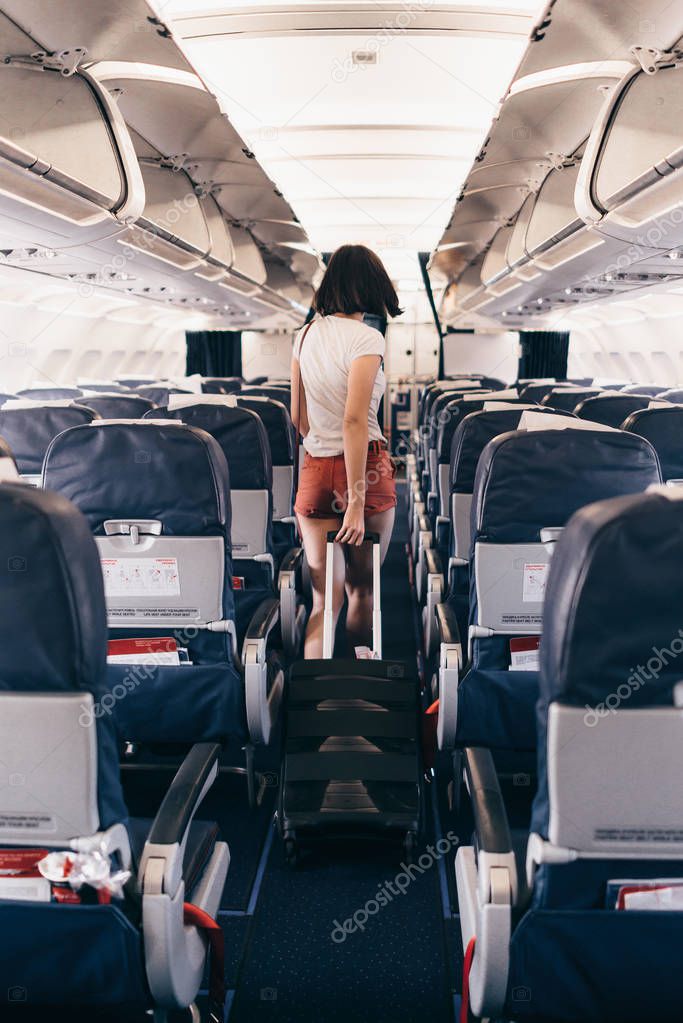 Back view of young woman walking the aisle on plane