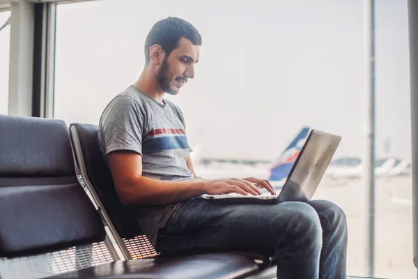 年轻人在机场航站楼使用笔记本电脑 — 图库照片