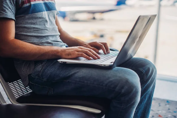 Przycięty obraz człowieka za pomocą laptopa do pisania maili w terminalu lotniska — Zdjęcie stockowe