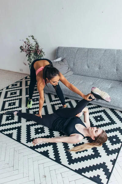 Fit jonge vrouw doen rekoefeningen met behulp van persoonlijke trainer thuis — Stockfoto