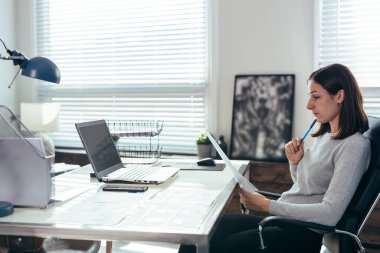 Ofis masasında belgelerle çalışan bir kadın..