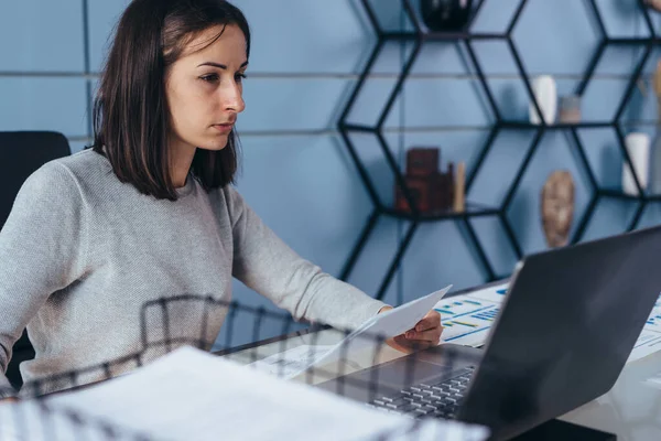 Женщина сидит в офисе и работает на ноутбуке — стоковое фото