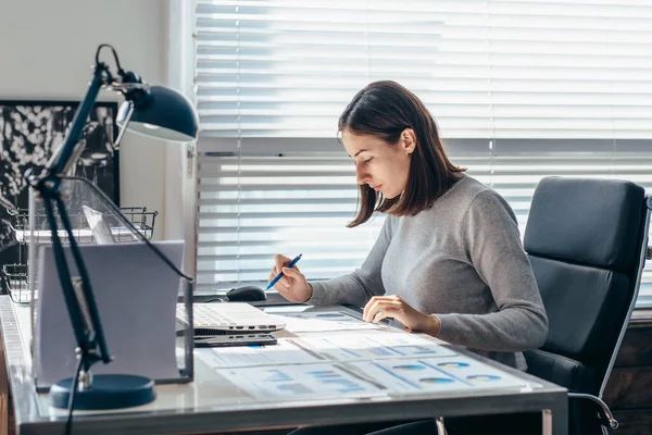 Kvinna som arbetar vid sitt skrivbord, antecknar — Stockfoto