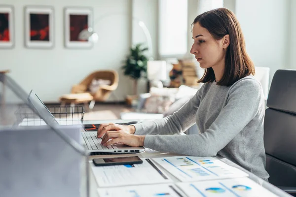 Ung kvinna upptagen med att arbeta på hemmakontoret — Stockfoto