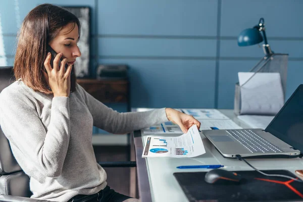 Žena mluví na mobilním telefonu pracuje na svém stole. — Stock fotografie