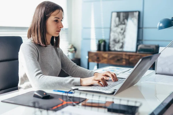 女人坐在办公桌前使用笔记本电脑。办公室里的女商人在笔记本电脑上工作 — 图库照片