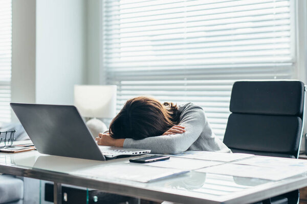 Young woman in office at her workplace is tired and resting