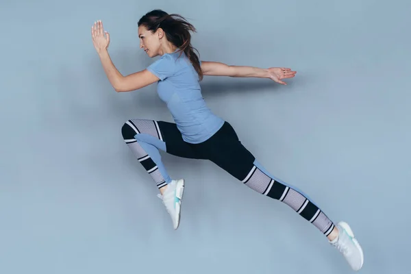 Mujer fitness haciendo ejercicio en casa, saltando y corriendo, haciendo ejercicios intensos —  Fotos de Stock