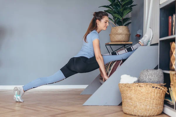 Flexibele vrouw doet voor split stretching oefening thuis. — Stockfoto