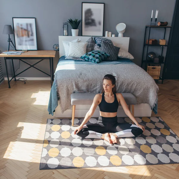 Fitness-Frau in Sportkleidung sitzt auf dem Boden im Schlafzimmer. — Stockfoto