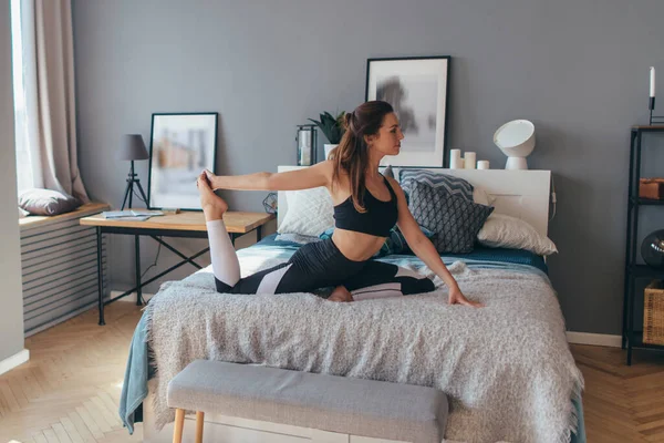 Mujer joven haciendo ejercicio en casa. Entrenamiento matutino en el dormitorio . —  Fotos de Stock