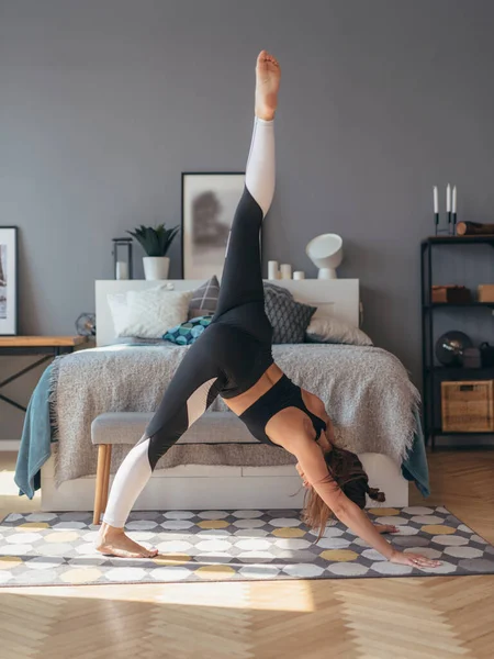 健身女人在家里练习瑜伽，她在前面弯腰做伸展运动 — 图库照片