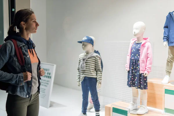 Jeune femme se tient près de la fenêtre du magasin enfants usure. — Photo