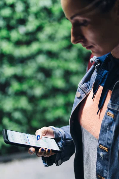 Chica utiliza un teléfono inteligente para navegar por la ciudad. Viendo la ruta, buscando una dirección, navegando por las calles de la ciudad —  Fotos de Stock