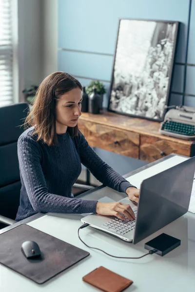 Jeune femme travaillant avec un ordinateur portable au bureau. — Photo