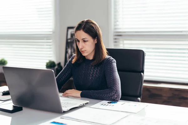 Femme s'assoit à table et travaille avec un ordinateur portable. Enseignement indépendant ou en ligne. — Photo