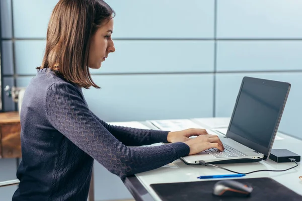 Žena v práci ve své kanceláři pracuje s notebookem. — Stock fotografie