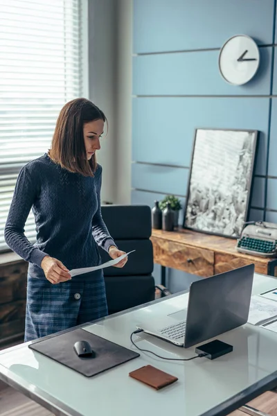 Kvinnan på kontoret står vid bordet och har dokument. — Stockfoto