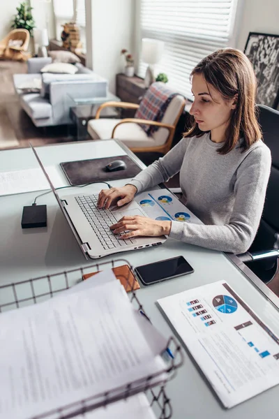 Ung kvinna arbetar vid ett skrivbord på sitt hemkontor — Stockfoto