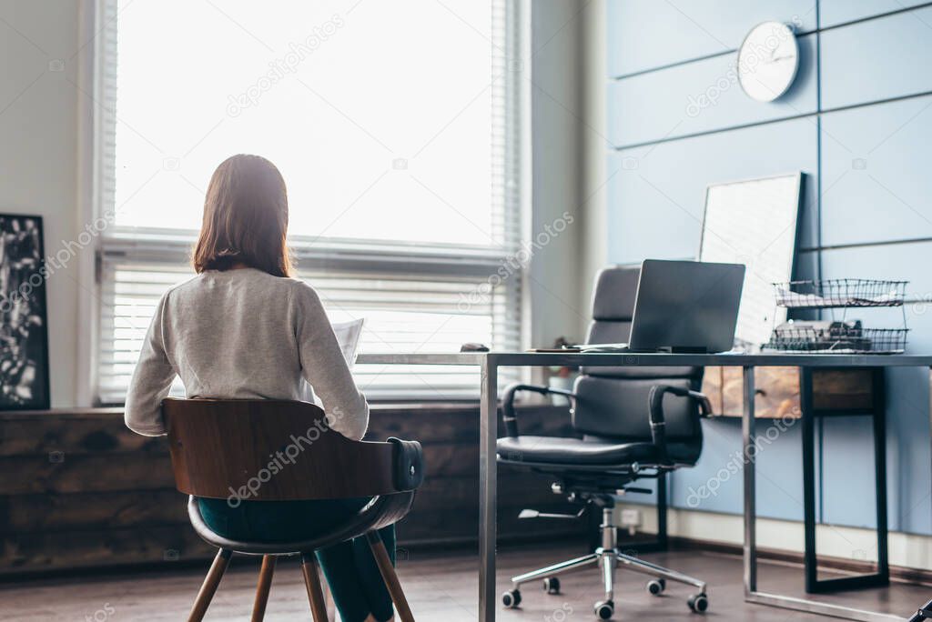 Woman sits in the managers office waiting for a meeting.