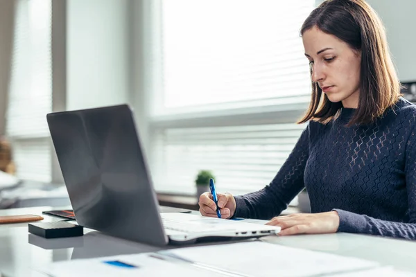 Mujer trabajando en su escritorio, tomando notas. —  Fotos de Stock