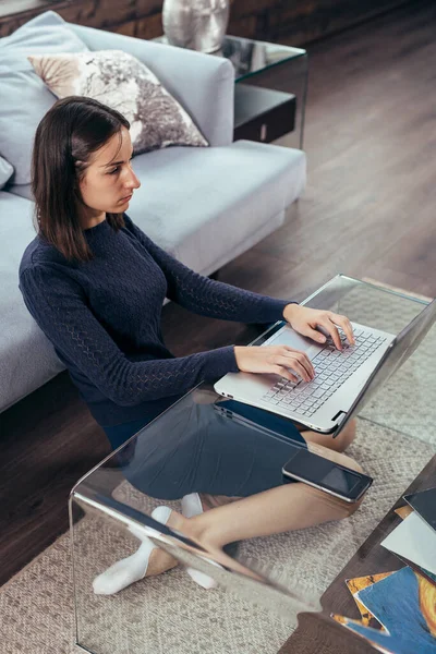 Chica con un ordenador portátil se sienta en casa en el suelo —  Fotos de Stock