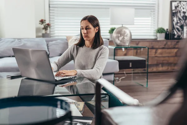 Dizüstü bilgisayarda çalışan bir kadın evinde yerde oturuyor.. — Stok fotoğraf