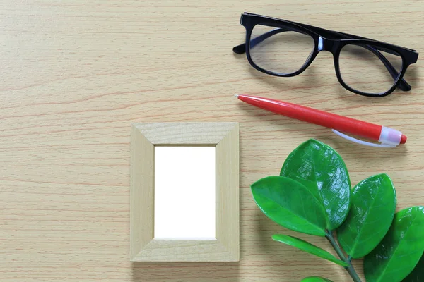 Vintage photo frame and spectacles near red pen placed on brown wooden floor and have copy space for design in your work concept.
