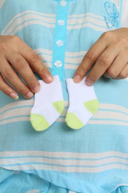 Mide için tasarım işiyle gebelik kavramı hakkında küçük bir çift çorap tutan hamile anneler.