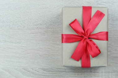 Noel ve yeni yıl kavram tasarımınız için ahşap zemin üzerinde kırmızı yay ile kahverengi hediye kutusu.