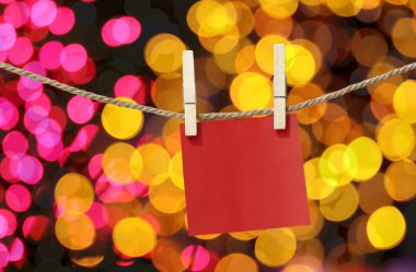 Clothesline tasarımı için Noel günü bokeh ışık arka plan, tasarım fikirleri için önemli gün için Not defteri üzerinde asılı boş kırmızı kağıt notları.