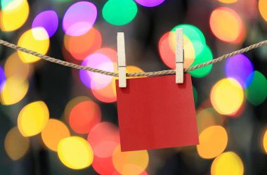 Clothesline tasarımı için Noel günü bokeh ışık arka plan, tasarım fikirleri için önemli gün için Not defteri üzerinde asılı boş kırmızı kağıt notları.