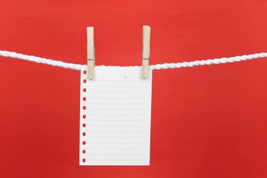 Boş not kağıdı clothesline üzerinde asılı ve kopya alanınız için senin iş kavramı tasarımında kırmızı arka plan ile.