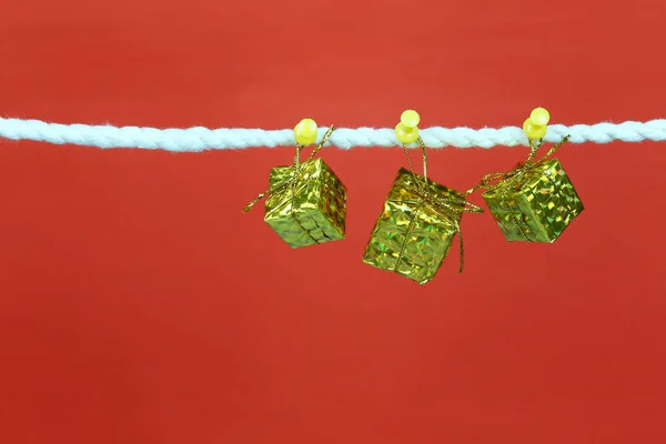 Gold gift box hang on the clothesline and have copy space with red background for design in your work concept.