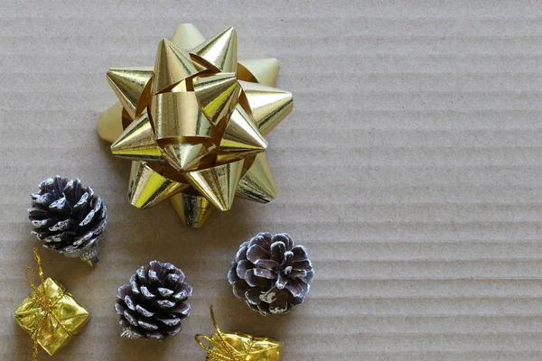 ゴールド リボンと松ぼっくりあなたの仕事でデザインのコピー スペース クリスマス コンセプトのブラウン ハード紙の上 — ストック写真