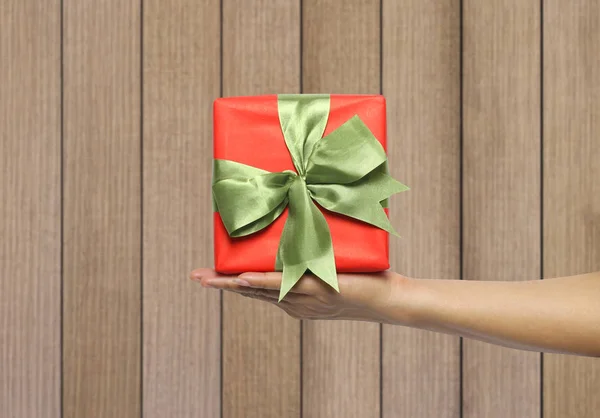 Hand Van Vrouwen Met Een Rode Giftdoos Muur Houten Achtergrond — Stockfoto