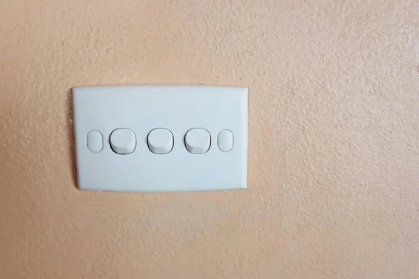 Przycisk białego przełącznika na pomarańczowej ścianie. — Zdjęcie stockowe