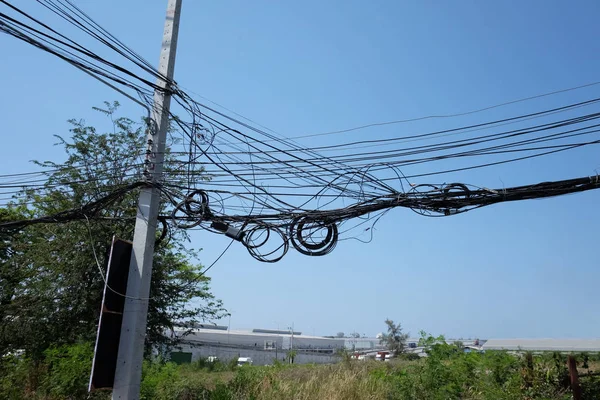 Kabeldrähte an den Strommasten sind verwirrt, unordentliche Signalleitung. — Stockfoto