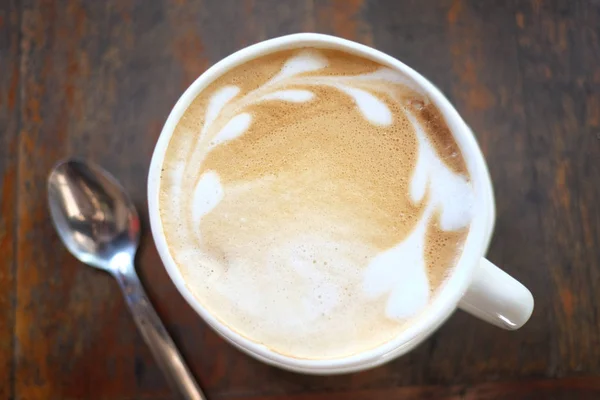 Latte káva v bílém hrnku na dřevěném stole. — Stock fotografie