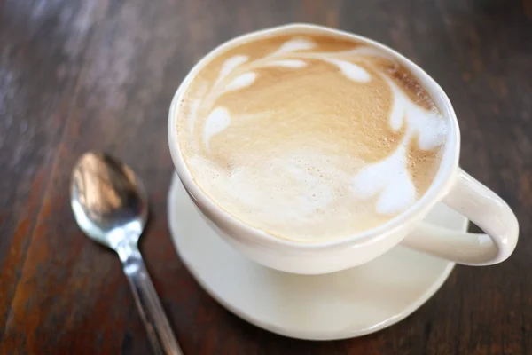 Latte káva v bílém hrnku na dřevěném stole. — Stock fotografie