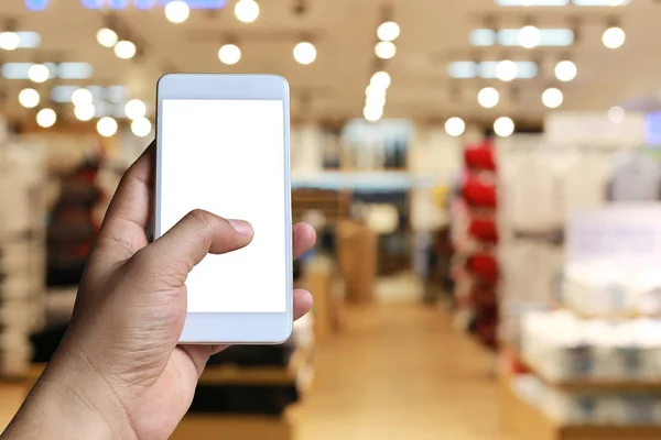 Hand av en man som innehar smartphone-enhet i Blur shopping mal — Stockfoto