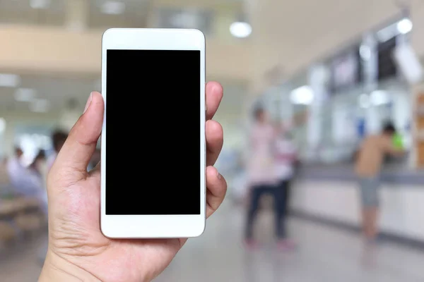 Hand av en man som innehar smartphone-enhet på Blur Hospital backgro — Stockfoto